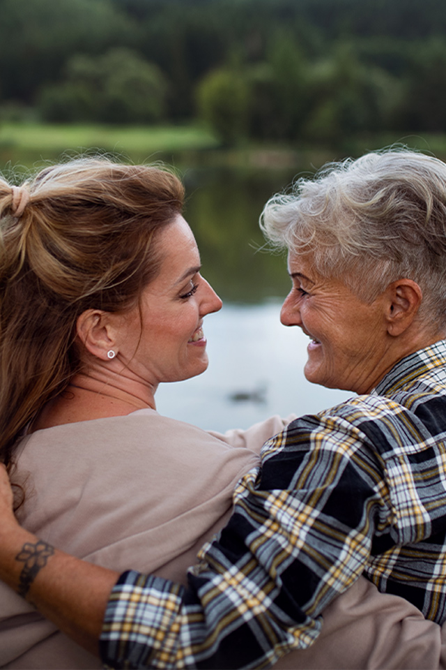 mother and daughter embracing with lake in background dementia